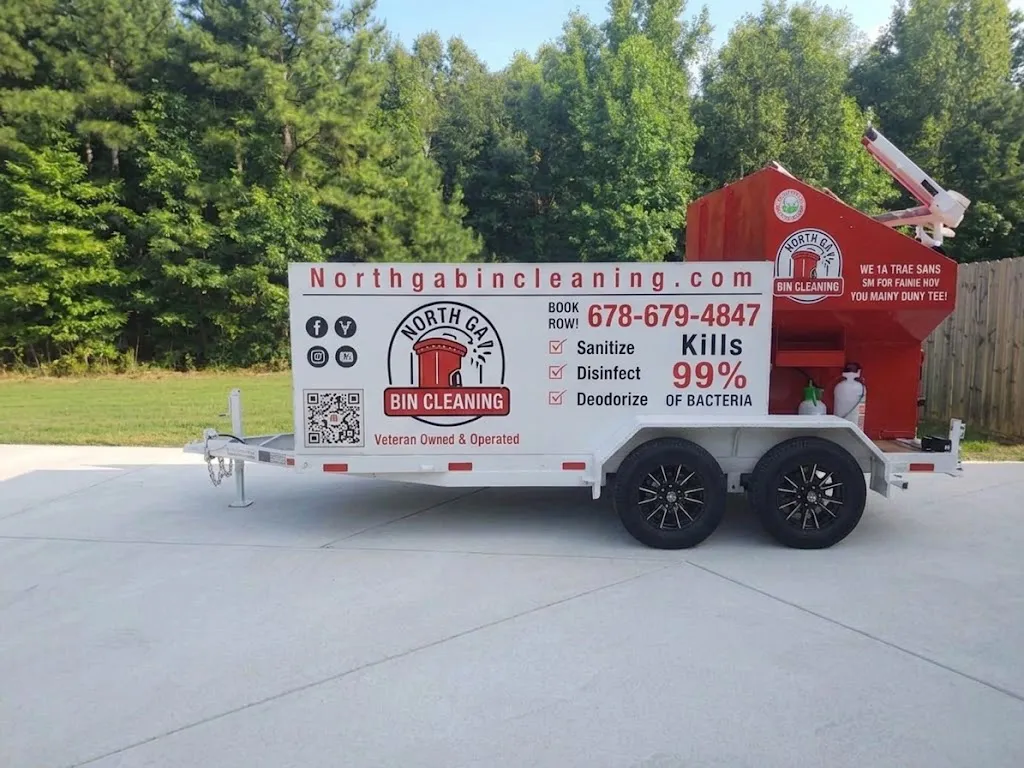 Red trash bin being pressure washed against graffiti brick wall